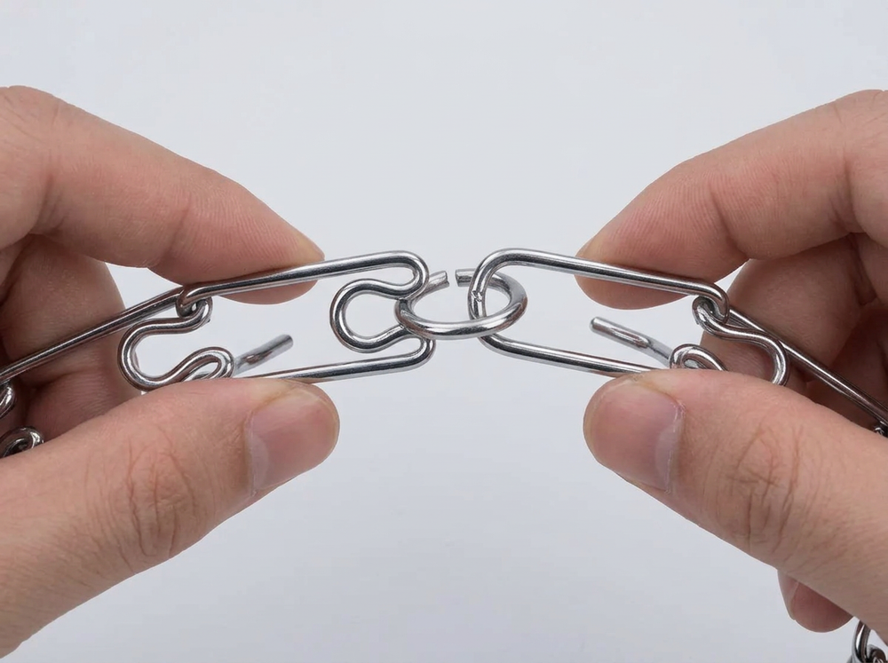 Hands adjusting individual links on chrome plated steel prong dog collar