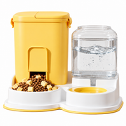 Yellow and white automatic pet food and water dispenser with kibble bowl and clear water container on a white background.